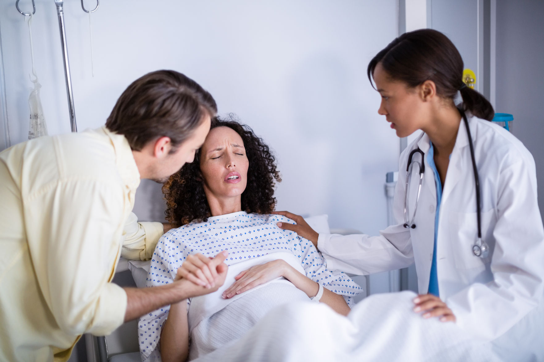 Doctor and man comforting pregnant woman in ward
